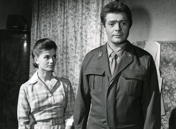 Scena del film "Fantasmi a Roma" - Regia Pietrangeli, Antonio, 1961 - Un'attrice non identificata, a sinistra, osserva Marcello Mastroianni con il viso pieno di macchie cutanee, a destra, che pone lo sguardo fisso davanti a sé.
