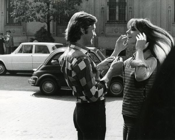 Scena del film "Una farfalla con le ali insanguinate" - Regia Tessari, Duccio, 1971 - Helmut Bergher sorridente, a sinistra, porge un oggetto non identificato a Ida Galli che allegramente si porta le mani ai capelli.