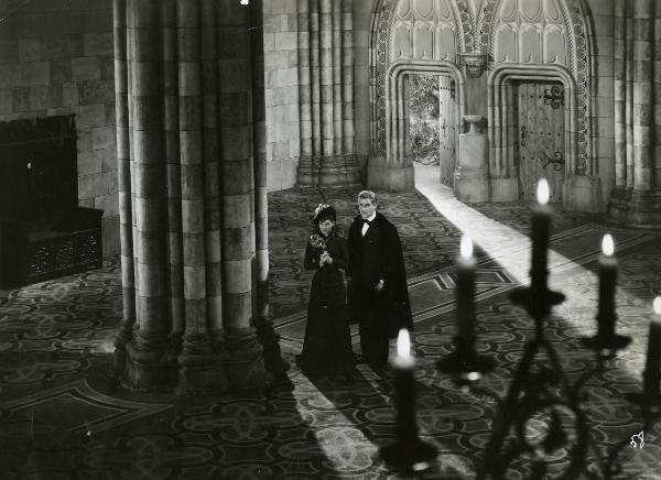 Scena del film "Fedora" - Regia Mastrocinque, Camillo, 1942 - Nella navata di una chiesa, Luisa Ferida, con le mani giunte, e Amedeo Nazzari rivolgono lo sguardo verso sinistra.
