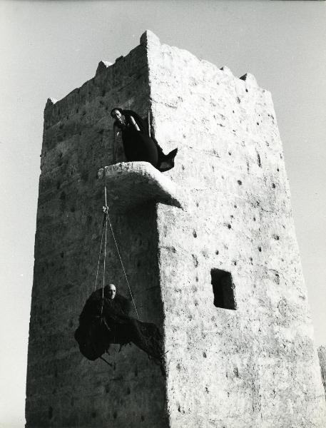 Scena del film "Fellini-Satyricon" - Fellini, Federico, 1969 - Un'attrice non identificata è appoggiata a una sporgenza da cui pende una corda che sostiene un secondo attore non identificato che rivolge lo sguardo verso destra.