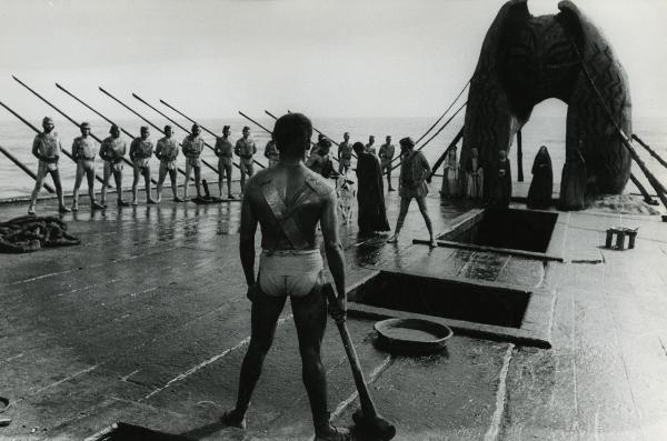 Scena del film "Fellini-Satyricon" - Fellini, Federico, 1969 - In primo piano, un attore non identificato di spalle tiene in mano un martello. Di fronte, tre attori non identificati gli avvicinano una mucca. In secondo piano, attori non identificati.