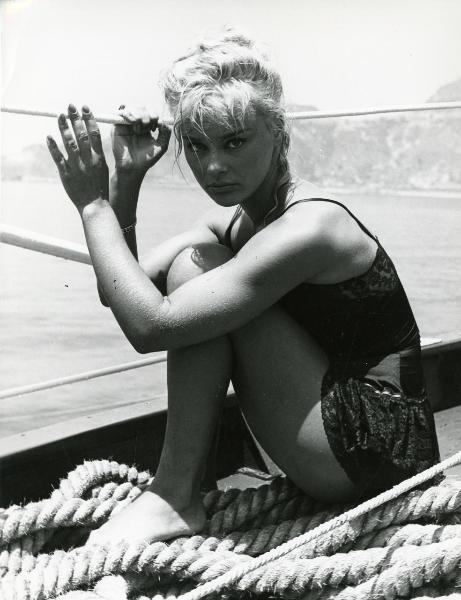 Scena del film "Femmine di lusso" - Bianchi, Giorgio, 1960 - Figura intera di un'attrice non identificata seduta sul pontile di una barca che si attacca a delle corde.
