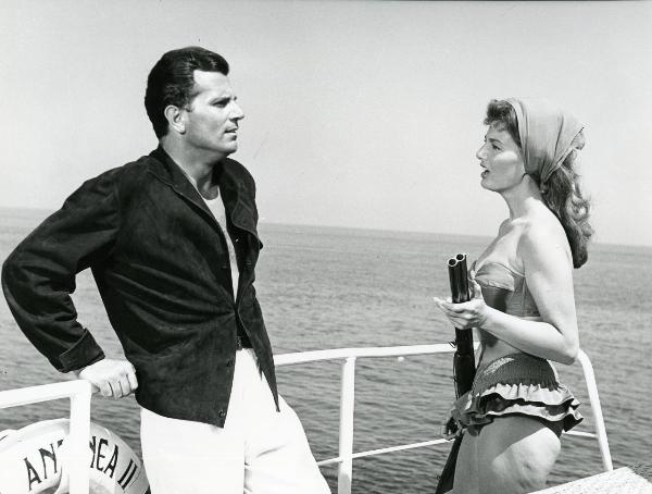 Scena del film "Femmine di lusso" - Bianchi, Giorgio, 1960 - Chantal Caprice, a destra con un fucile in mano, discute con un attore non identificato a sinistra, appoggiato alla ringhiera di una nave.
