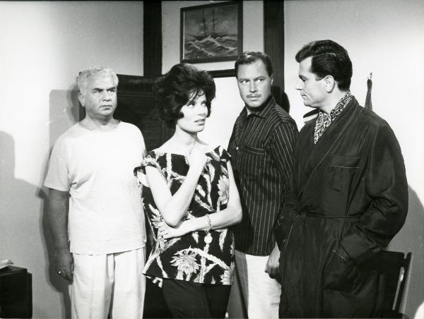 Scena del film "Femmine di lusso" - Bianchi, Giorgio, 1960 - Belinda Lee, al centro, e un attore non identificato si osservano vicendevolmente. In secondo piano Gino Cervi, a sinistra, e Ivan Desny, al centro, li osservano.
