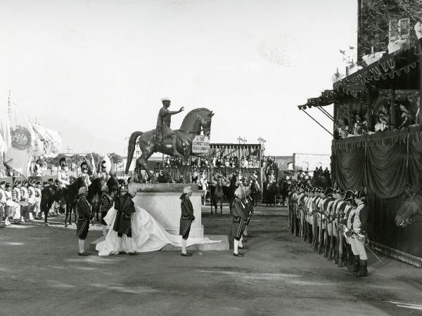 Scena del film "Ferdinando I, Re di Napoli" - Franciolini, Gianni, 1959 - Davanti a un palco: alcuni attori non identificati, al centro in vesti di servitori, rimuovono un telo da una statua che riporta un cartello. Attorno, attori non identificati.