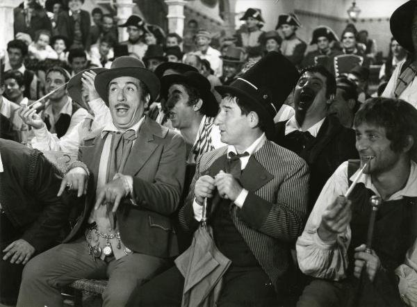 Scena del film "Ferdinando I, Re di Napoli" - Franciolini, Gianni, 1959 - Renato Rascel, al centro, osserva Peppino De Filippo, alla sua destra, che fa il segno delle corna con le mani e guarda davanti a sé. Attorno, attori non identificati.