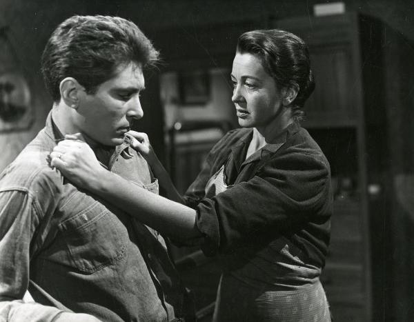 Scena del film "Il ferroviere" - Germi, Pietro, 1956 - Luisa Della Noce, a destra, afferra saldamente le spalle della camicia di Renato Speziali, a sinistra, che si ritrae e rivolge lo sguardo verso il basso.
