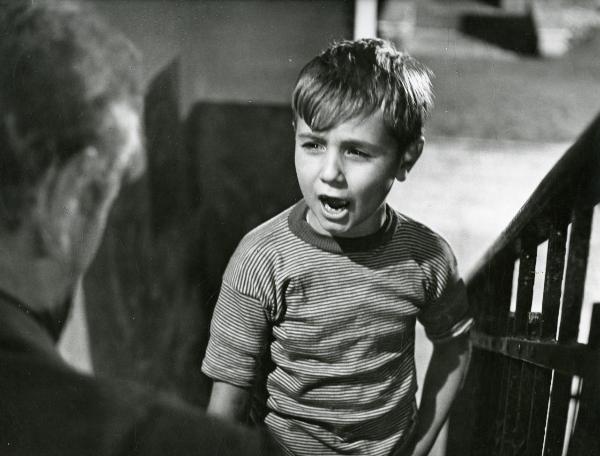 Scena del film "Il ferroviere" - Germi, Pietro, 1956 - Mezza figura di Edoardo Nevola che, vicino al corrimano di una scala, discute con un attore non identificato di spalle a sinistra.
