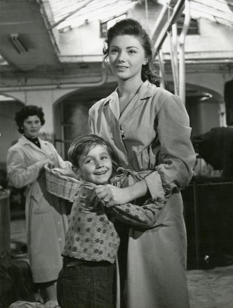 Scena del film "Il ferroviere" - Germi, Pietro, 1956 - In primo piano, Sylva Koscina e Edoardo Nevola si abbracciano e rivolgono lo sguardo a sinistra. In secondo piano, un'attrice non identificata, con una cesta di vimini in mano, li osserva.