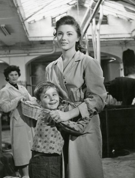 Scena del film "Il ferroviere" - Germi, Pietro, 1956 - In primo piano, Sylva Koscina e Edoardo Nevola si abbracciano e rivolgono lo sguardo a sinistra. In secondo piano, un'attrice non identificata, con una cesta di vimini in mano, li osserva.