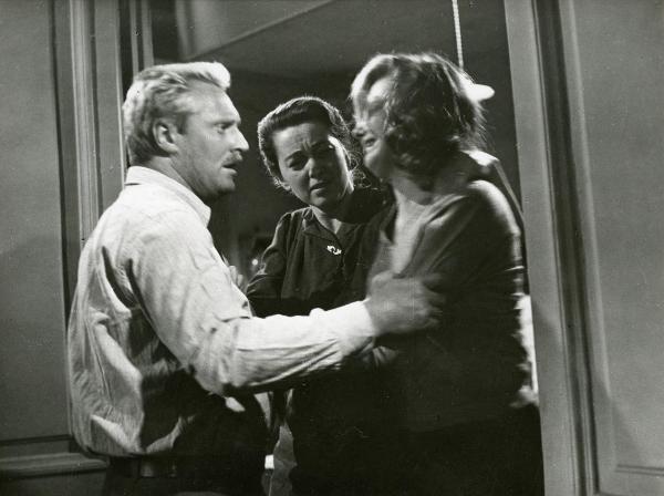 Scena del film "Il ferroviere" - Germi, Pietro, 1956 - Sotto lo stipite di una porta: Pietro Germi, afferra le braccia di un'attrice non identificata, a destra. Al centro, Luisa Della Noce, la osserva.
