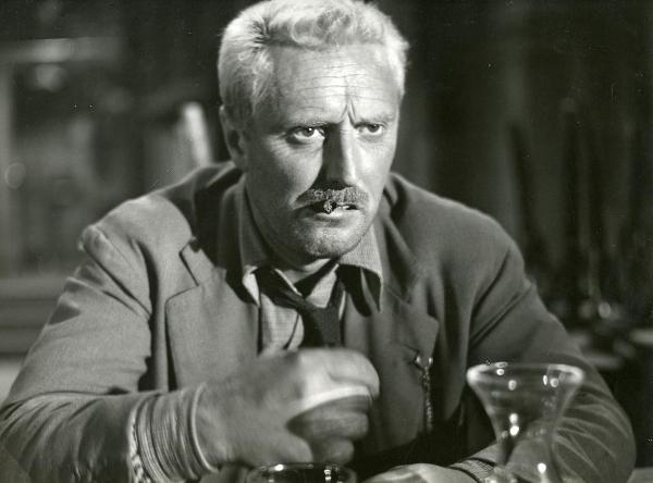 Scena del film "Il ferroviere" - Germi, Pietro, 1956 - Primo piano di Pietro Germi che, con un sigaro in bocca, rivolge uno lo sguardo di fronte a sé.

