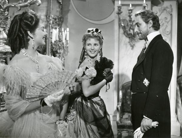 Scena del film "La fiammata" - Blasetti, Alessandro, 1952 - Rolf Tasna, a destra, con dei guanti in mano, e Eleonora Rossi Drago, a sinistra con un ventaglio in mano, osservano sorridenti Delia Scala, al centro, anch'ella con un ventaglio in mano.