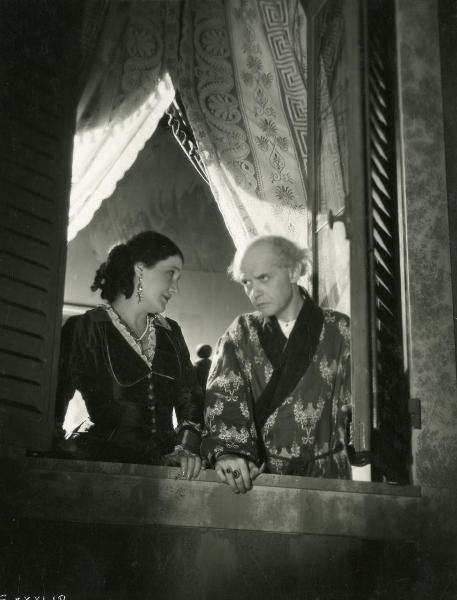 Scena del film "Figaro e la sua gran giornata" - Camerini, Mario, 1931 - Da una finestra aperta: un'attrice non identificata, a sinistra di profilo, osserva Gianfranco Giachetti, a destra in vestaglia, che rivolge lo sguardo verso sinistra.