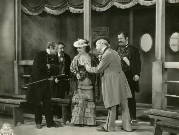 Scena del film "Figaro e la sua gran giornata" - Camerini, Mario, 1931 - Giachetti indica Gloria Leda e conversa con un attore non identificato a sinistra. In secondo piano, un attore non identificato, a sinistra, e Ceseri, a destra, li osservano.