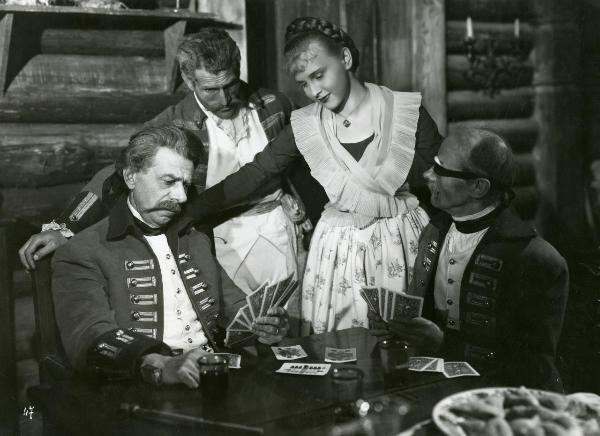 Scena del film "La figlia del capitano" - Camerini, Mario, 1947 - Seduto, Aldo Silvani, a sinistra in divisa militare, gioca a carte con un attore non identificato, a destra. In secondo piano, un attore non identificato e Irasema Dilian lo osservano.