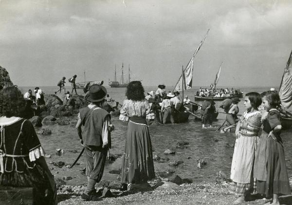 Scena del film "La figlia del corsaro verde" - Guazzoni, Enrico, 1940 - Due attrici non identificate a destra osservano Polidor e Doris Duranti, al centro di spalle, mentre guardano verso il mare.

