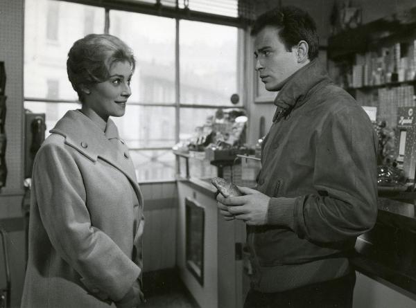 Scena del film "Un figlio d'oggi" - Girolami, Marino, 1961 - Mezze figure di Leonora Bianchi, a sinistra sorridente, e Ennio Girolami, a destra con una brioches in mano, che si osservano vicendevolmente.
