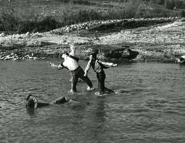 Scena del film "Un fiume di dollari" - Lizzani, Carlo, 1966 - Tom Hunter sferra un pugno a un attore non identificato in un fiume. Nell'acqua davanti a loro c'è un corpo immerso fermo.
