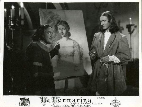 Scena del film "La fornarina" - Guazzoni, Enrico, 1942 - Walter Lazzaro, con in mano un carboncino, guarda verso Vinicio Sofia che, parlandogli, indica il disegno su cavalletto che si trova tra i due.