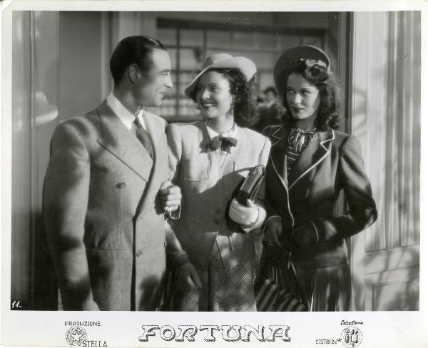 Scena del film "Fortuna" - Neufeld, Max, 1940 - A destra, Tony D'Algy guarda Maria Denis, al centro. A destra, Jone Salinas li osserva diffidente.
