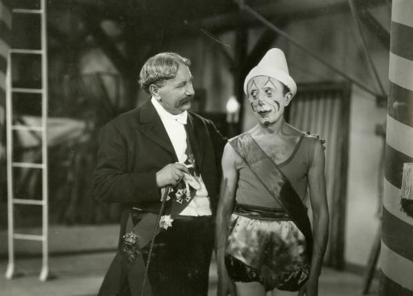 Scena del film "La forza bruta" - Bragaglia, Carlo Ludovico, 1941 - Claudio Ermelli, travestito e truccato da clown, guarda verso Olinto Cristina che lo stringe per una spalla con la mano sinistra.
