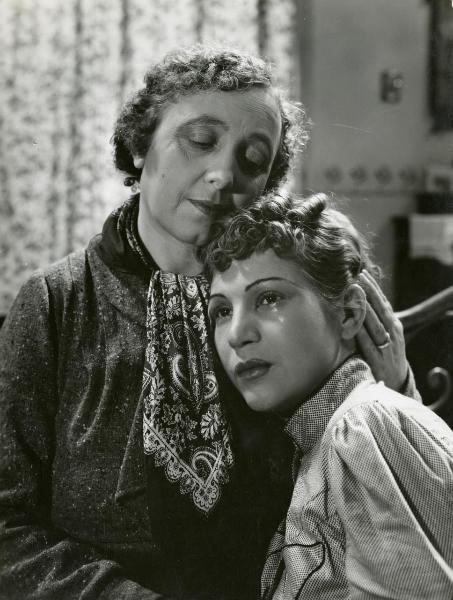 Scena del film "La fossa degli angeli" - Bragaglia, Carlo Ludovico, 1937 - Luisa Ferida, piangendo, si appoggia al petto della madre Annette Ciarli che la consola appoggiando una mano dietro la testa e la guancia sui capelli della ragazza.
