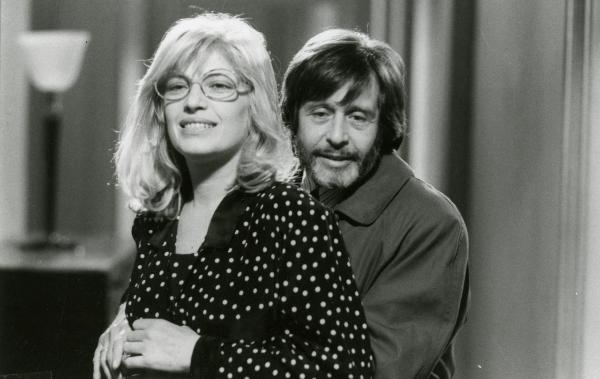 Scena del film "Francesca è mia" - Russo, Roberto, 1986 - In primo piano, Monica Vitti sorridente, guarda davanti a sé mentre un attore non identificato la abbraccia da dietro.

