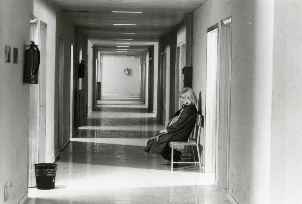 Scena del film "Francesca è mia" - Russo, Roberto, 1986 - Monica Vitti, di profilo seduta sulla sedia nel cOrridoio dell'ospedale, fissa davanti a sé verso il basso.
