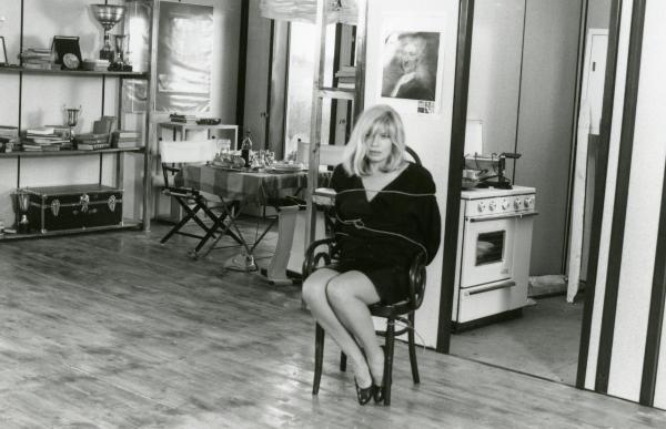 Scena del film "Francesca è mia" - Russo, Roberto, 1986 - Monica Vitti legata con una corda alla sedia in mezzo a una stanza con viso preoccupato e con i capelli scompigliati guarda davanti a sé.
