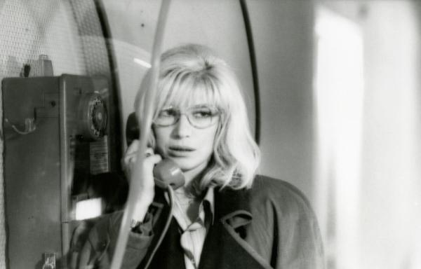 Scena del film "Francesca è mia" - Russo, Roberto, 1986 - Monica Vitti, appoggiata a un muro di fianco a un telefono a gettoni, tiene all'orecchio la cornetta mentre guarda alla sua destra.