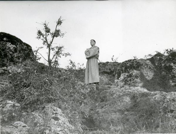 Scena del film "Francesco, giullare di Dio" - Rossellini, Roberto, 1950 - Tra le rocce e le sterpaglie, Nazario Gerardi in piedi e con le braccia conserte guarda dritto di fronte a sé.
