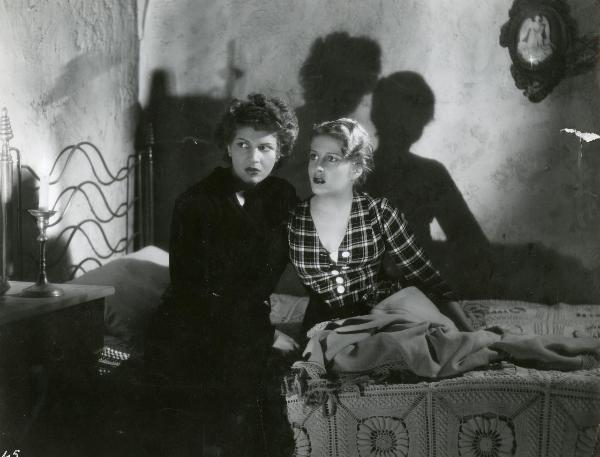 Scena del film "I fratelli Castiglioni" - D'Errico, Corrado, 1939 - Alla penombra di una lampada, su un letto: Luisa Ferida a sinistra e Vanna Vanni a destra, guardano verso sinistra.