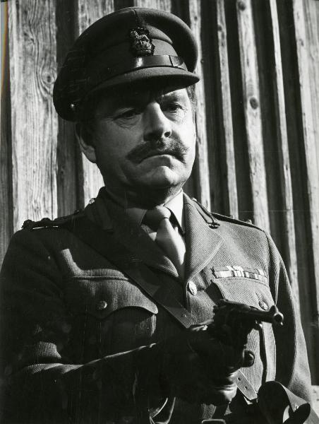 Scena del film "Fraulein doktor" - Lattuada, Alberto, 1969 - Mezza figura di Kenneth More in abiti militari mentre punta una pistola davanti a sé.