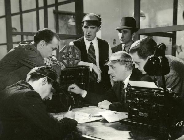 Scena del film "Freccia d'oro" - D'Errico, Corrado, 1935 - Vicino ad un apparecchio meccanico si riconosce Maurizio D'Ancora a sinistra appoggiato a braccia conserte sull'apparecchio. Attorno, attori non identificati.