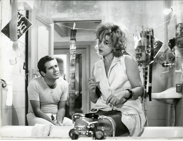 Scena del film "Frenesia dell'estate" - Zampa, Luigi, 1964 - In uno studio fotografico, Sandra Milo è seduta al centro e guarda in basso di fronte a lei. Dietro, Giampiero Littera la osserva.