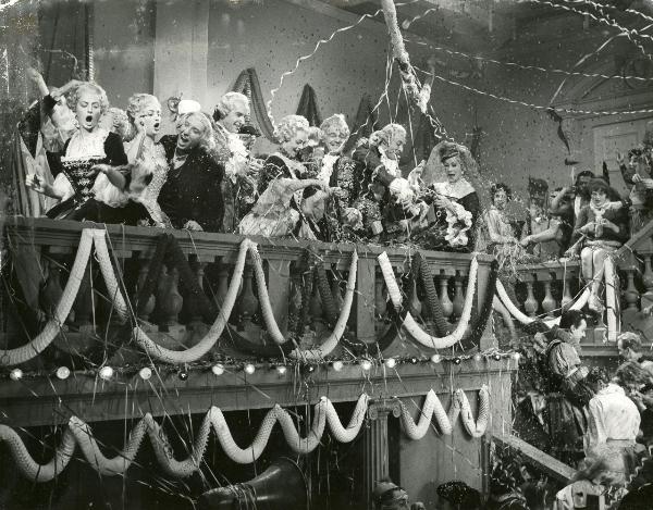 Scena del film "Frou - Frou" - Genina, Augusto, 1955 - Su un balcone, attrici e attori non identificati nelle vesti di nobili fanno festa. Al centro della scena, si riconosce Dany Robin.