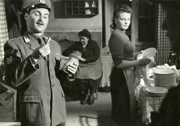 Scena del film "Fuga in Francia" - Soldati, Mario, 1948 - A sinistra, Gino Apostolo con in mano un barattolo di latta e un oggetto non identificato. A sinistra, Rosi Mirafiore mentre asciuga una pila di piatti. Dietro, un'attrice non identificata.