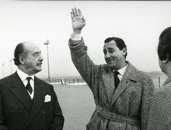 Scena del film "Fumo di Londra" - Sordi, Alberto, 1966 - Michael Trubshawe, a sinistra, e Alberto Sordi, a destra. Sordi tiene il braccio destro elevato come in segno di saluto. A sinistra un'attrice non identificata.