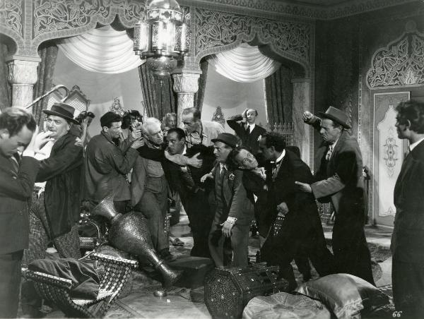 Scena del film "Fumeria d'oppio" - Matarazzo, Raffaello, 1947 - In una sala, arredata da tappeti, tende, pouf, cuscini e vasi, un gruppo di attori non identificati si sta prendendo a botte.