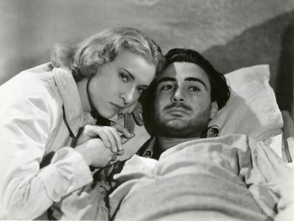 Scena del film "Fumeria d'oppio" - Matarazzo, Raffaello, 1947 - Primo piano di Armando Francioli a destra e Mariella Lotti a sinistra. L'attore guarda in alto a destra mentre lei ha lo sguardo rivolto verso la cinepresa. I due si tengono per mano.