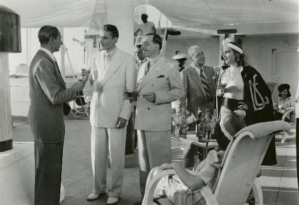 Scena del film "Fuochi d'artificio" - Righelli, Gennaro, 1938 - Da sinistra a destra: Romolo Costa e Amedeo Nazzari mentre brindano; tre attori non identificati; Linda Pini guarda i tre attori che brindano. Vicino a lei, Luigi Carini.