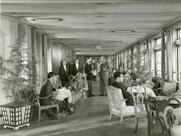 Scena del film "Fuochi d'artificio" - Righelli, Gennaro, 1938 - In una sala da pranzo: al centro, due attori non identificati in piedi si guardano. Dietro di loro, due attori non identificati nei panni di camerieri guardano verso la cinepresa.