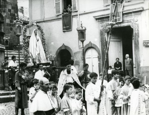 Scena del film "Fuoco" - Baldi, Gian Vittorio, 1969 - Durante una processione: in primo piano, attori non identificati. In fondo, il baldacchino con un Santo attorniato da una corona di fiori. In alto, tre attori non identificati.