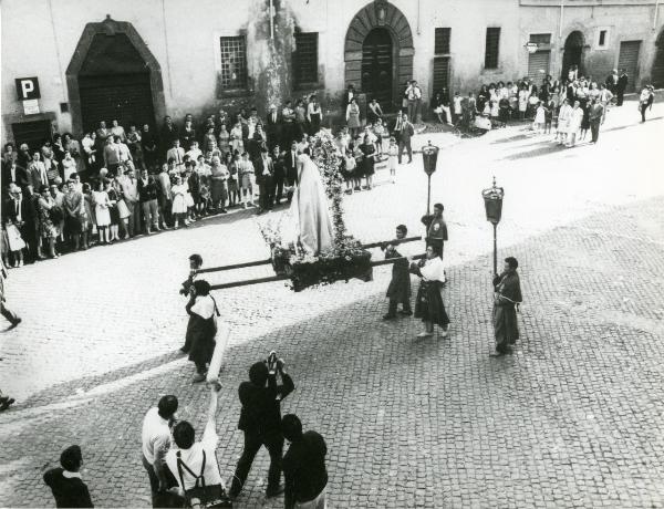 Scena del film "Fuoco" - Baldi, Gian Vittorio, 1969 - Una folla guarda passare un baldacchino con sopra la statua di un santo. Esso è trasportato da quattro attori non identificati. A sinistra, alcuni attori non identificati riprendono la scena.