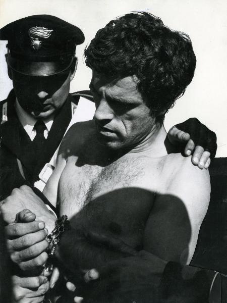 Scena del film "Fuoco" - Baldi, Gian Vittorio, 1969 - Primo piano di Mario Bagnato a torso nudo mentre viene arrestato da Giorgio Maulini nei panni di carabiniere. Nella scena si vedono altre tre mani di attori non identificati.