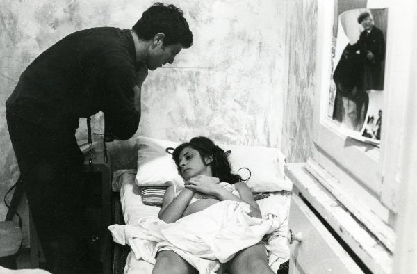 Scena del film "Fuoco" - Baldi, Gian Vittorio, 1969 - Su un letto: Lydia Biondi giace in biancheria intima semicoperta solo da un lenzuolo. Tiene le due mani sopra il petto e guarda verso sinistra. Chinato su di lei, Mario Bagnato la guarda.