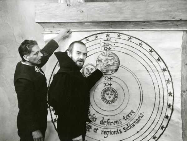 Scena del film "Galileo" - Cavani, Liliana, 1968 - Davanti ad una piantina del sistema solare, Cyril Cusack, indicando con la mano sinistra la mappa, ha lo sguardo rivolto verso la cinepresa. Dietro, un attore non identificato.