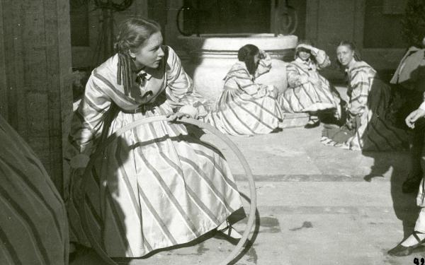 Scena del film "Un garibaldino al convento" - De Sica, Vittorio, 1942 - Accovacciata sulla sinistra, Carla Del Poggio tiene tra le mani un cerchio in legno. Dietro, tre attrici non identificate in abiti collegiali.