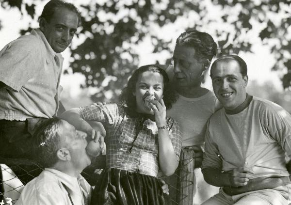 Fotografia sul set di "Gatta ci cova" - Righelli, Gennaro, 1937 - Al centro, Elli Parvo che mette in bocca un frutto ad un attore non identificato. Dietro di lei, due attori non identificati. A destra, il regista Gennaro Righelli.